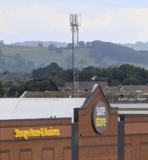 Image of a cell tower behind a store and in front of some hills