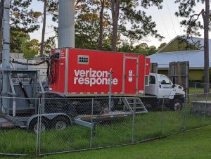 A red "Verizon Response" truck is parked in a fenced-off area under a COW deployment in Gulf Shores, Alabama.