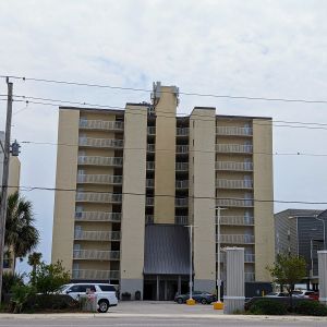 A beige beachfront condominium building with a T-Mobile macro site located on the upper middle section.